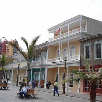 Paseo Baquedano en Iquique con edificaciones patrimoniales de madera y turistas caminando por la emblemática calle histórica del norte de Chile.